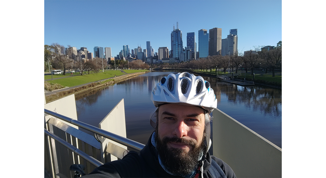 Un étudiant à vélo devant la ville de Melbourne en Australie