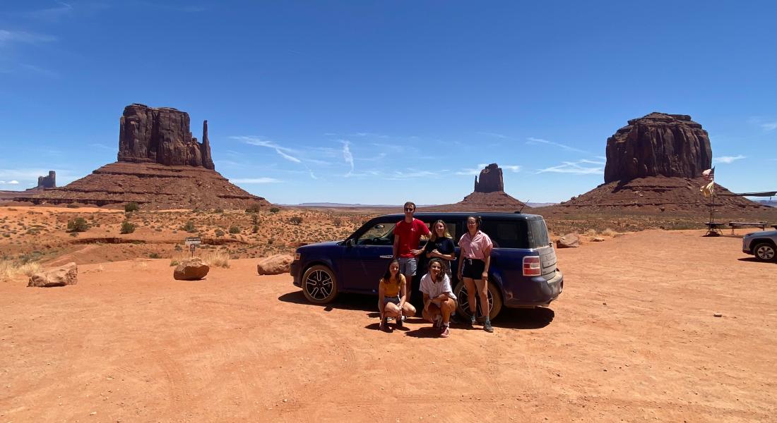 Cinq personnes devant une voiture dans un désert américain