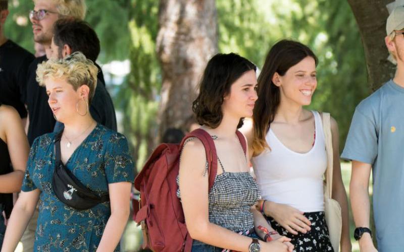 Photo d'étudiants et étudiantes de l'ENTPE, souriants, debout sous des arbres, en train de discuter 